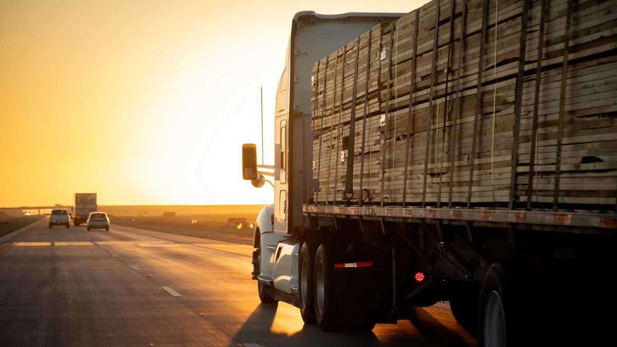 big rig drives on highway with full load of wood